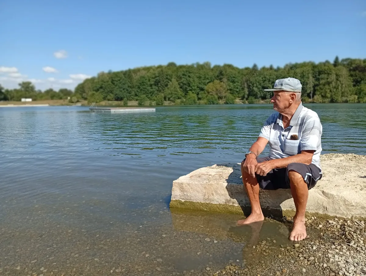 Senior sedí na kameni u klidného jezera