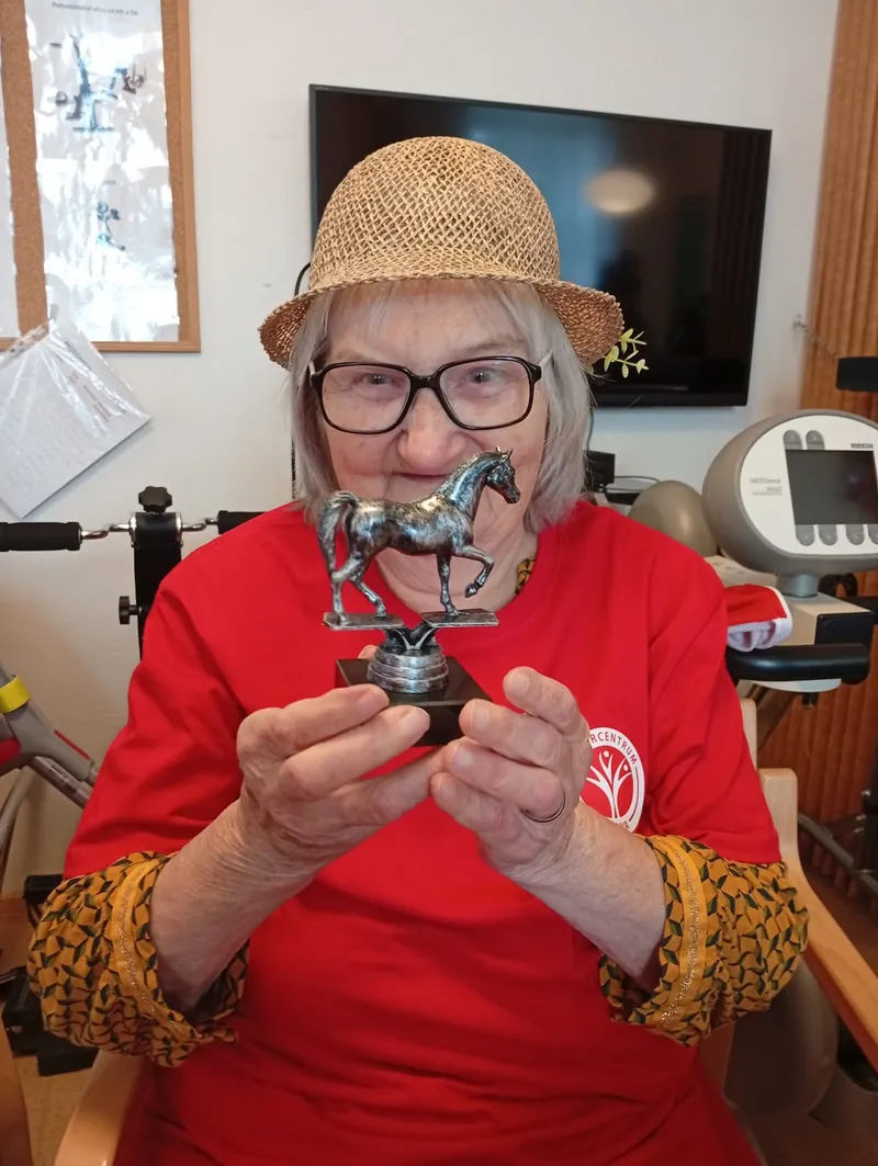 Seniorka ve slaměném klobouku s malou sošku koně