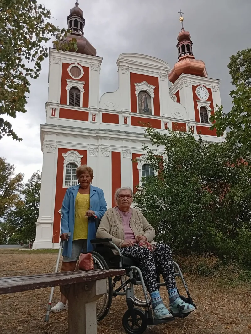 Seniorky u poutního kostela, jedna na vozíku